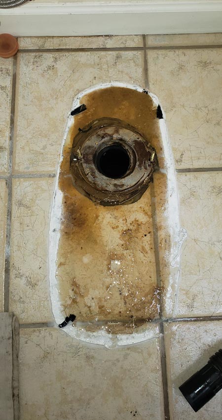 toilet being replaced showing wax ring and flange in footprint of removed toilet