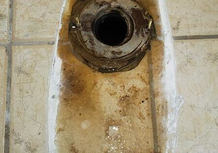 toilet being replaced showing wax ring and flange in footprint of removed toilet
